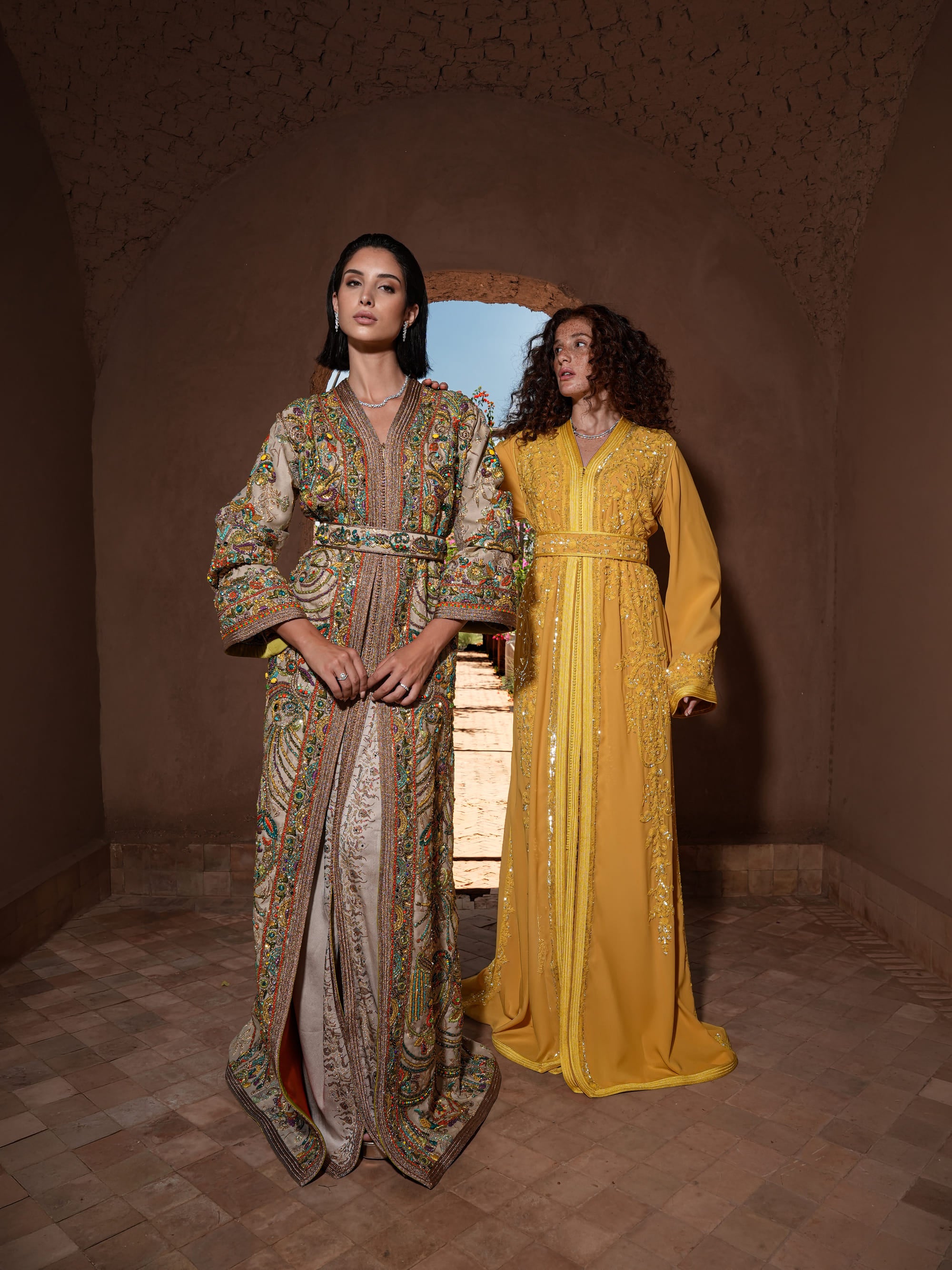 Mosaic Alcove beige silk Moroccan kaftan with polychrome beaded paisley embroidery in a Persian garden motif, shown alongside a second look